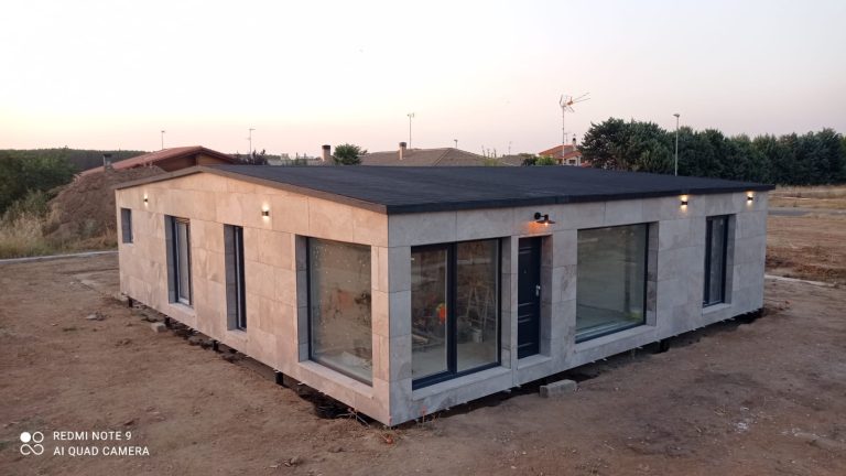 Casa modular con fachada de piedra en su parcela al atardecer